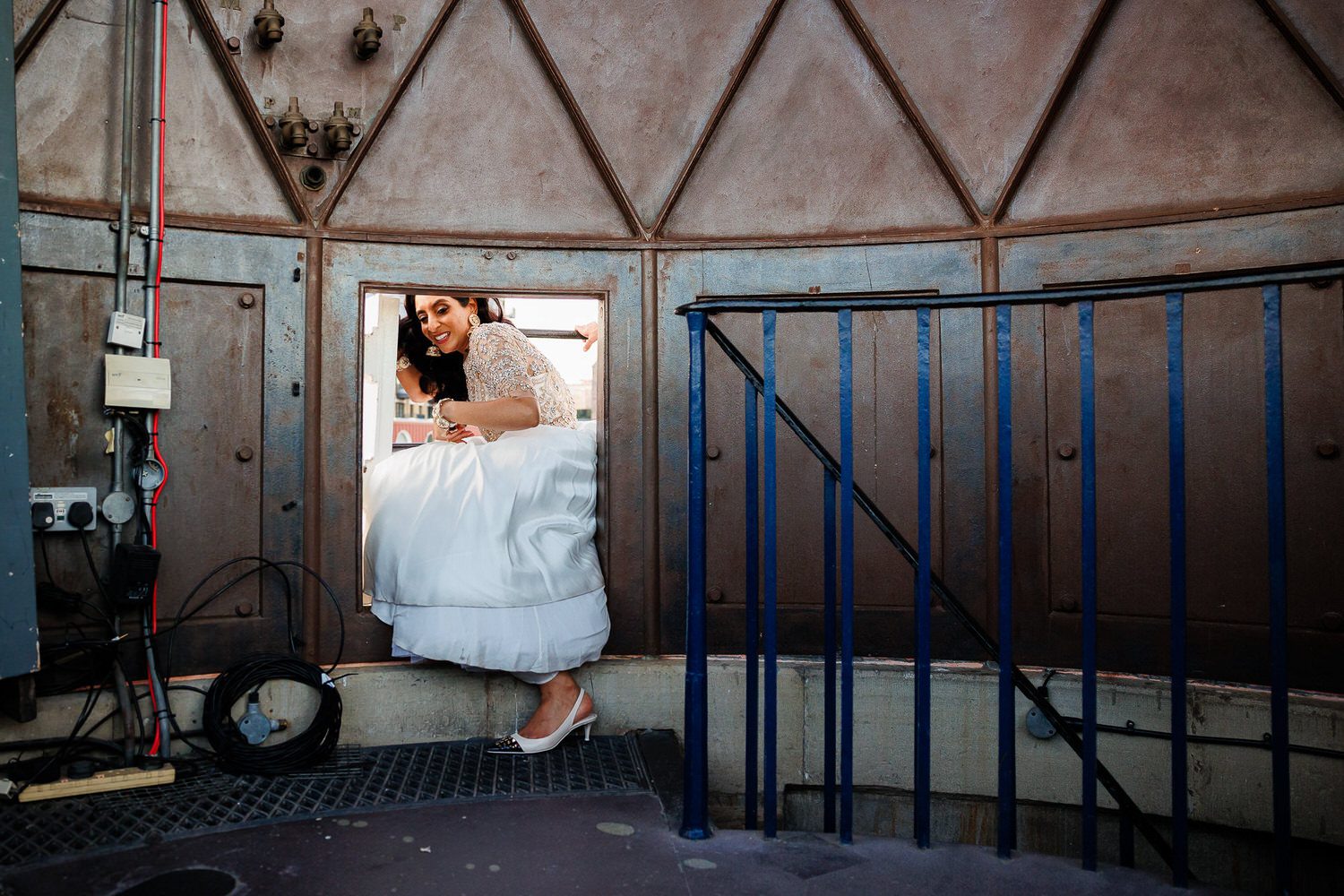Bride squeezing through hatch, London Wedding