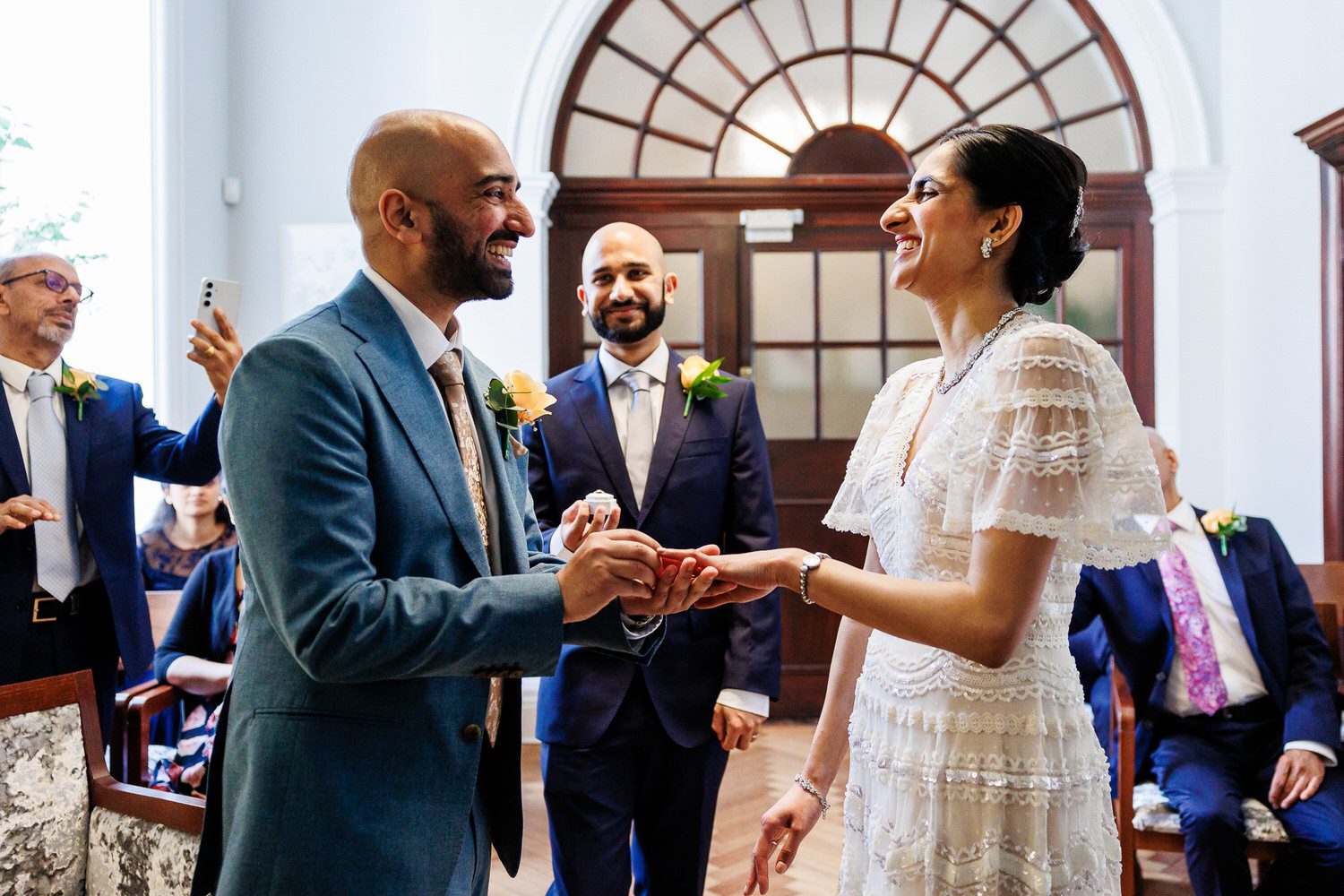 Groom placing wedding ring on bride