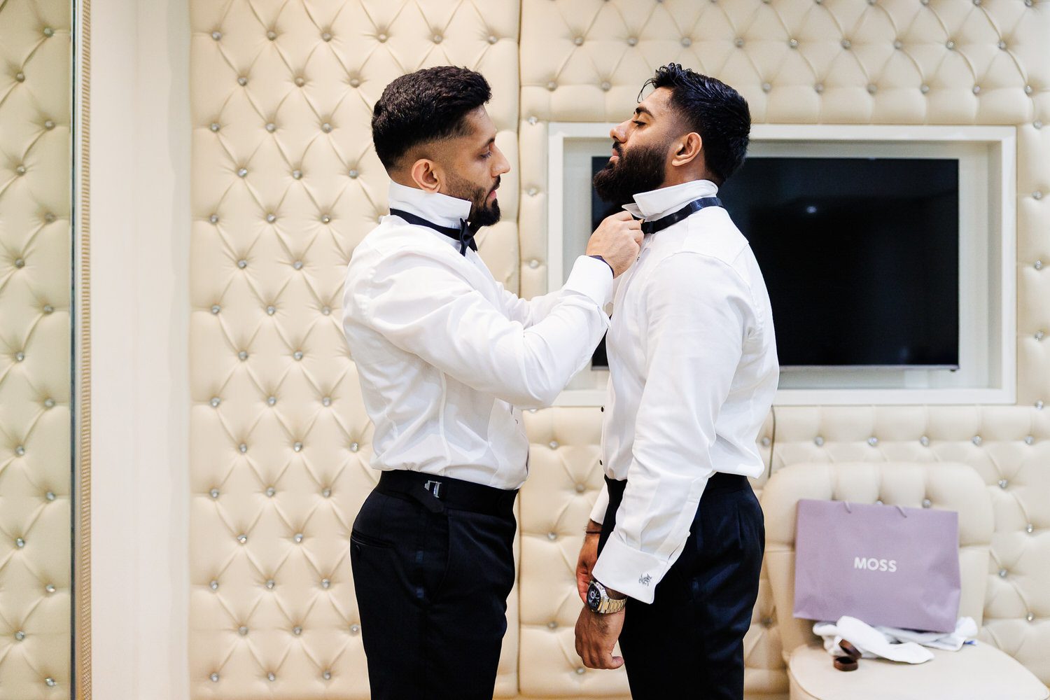 Groomsman helping groom with tie