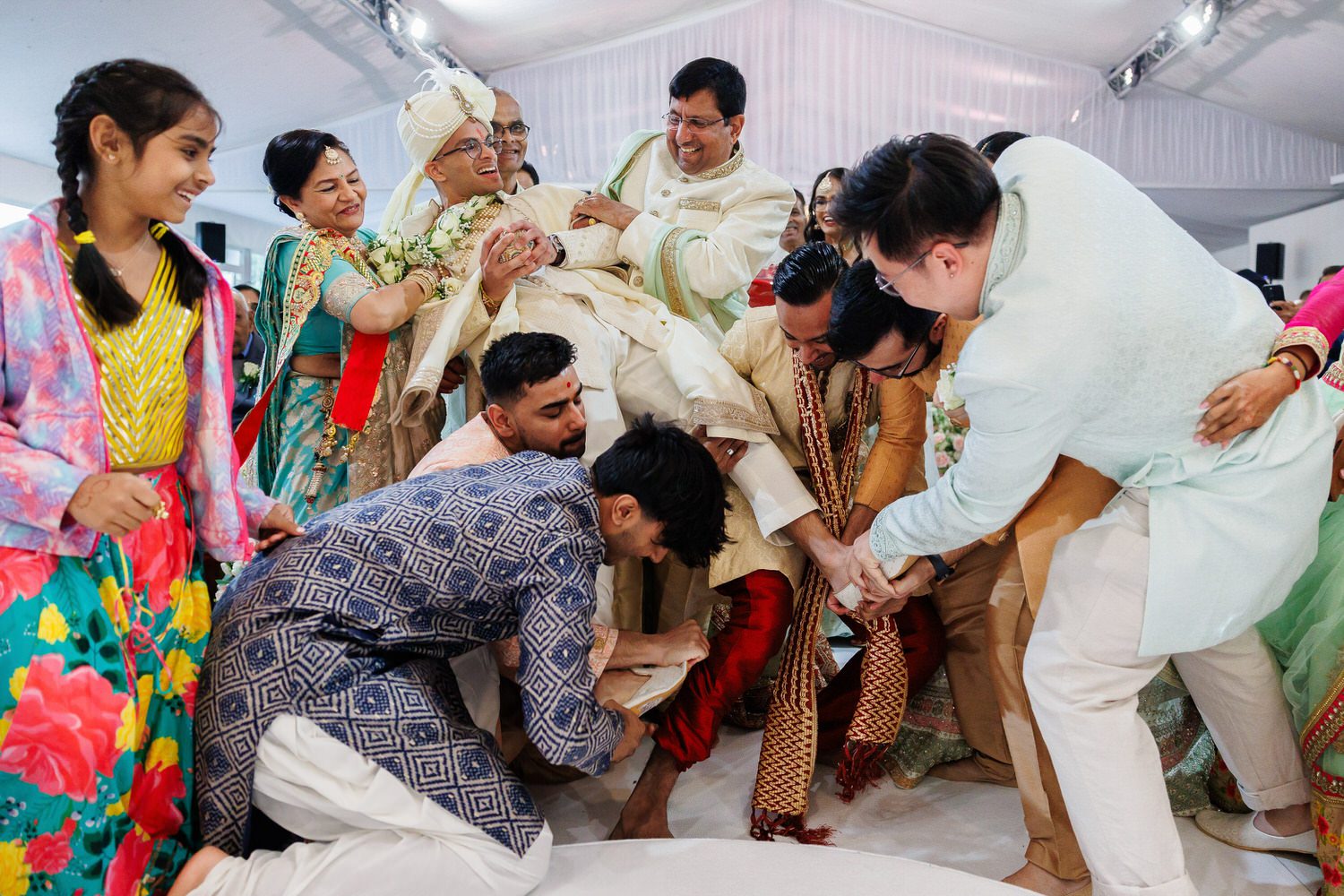 Asian wedding groom being lifted and having his shoes stolen