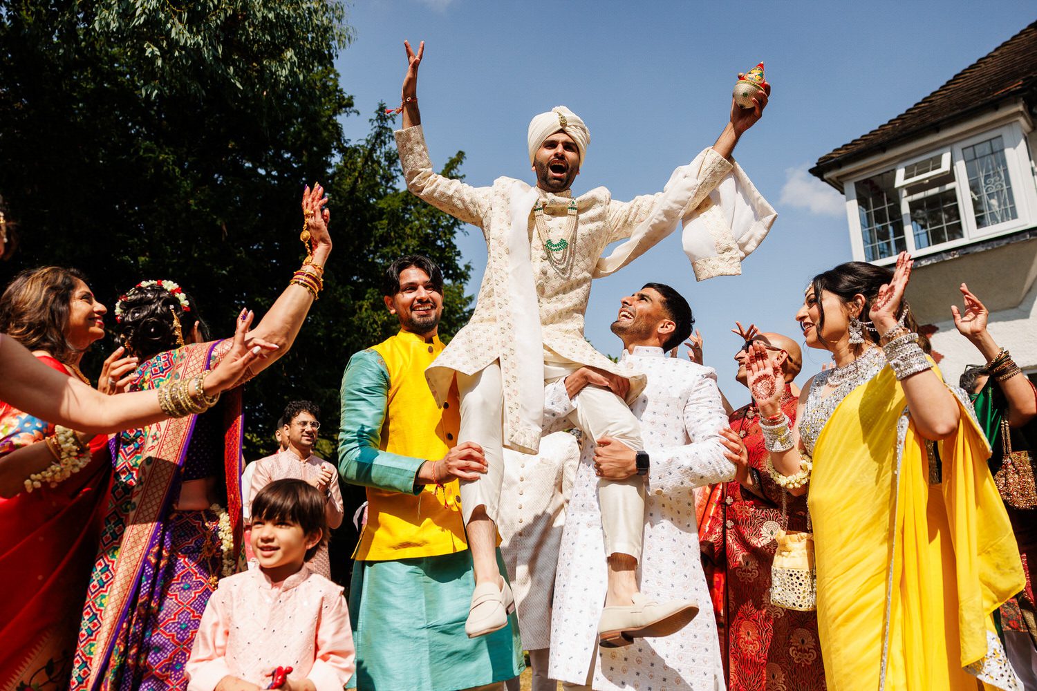 Groom being lifted into the air during procession