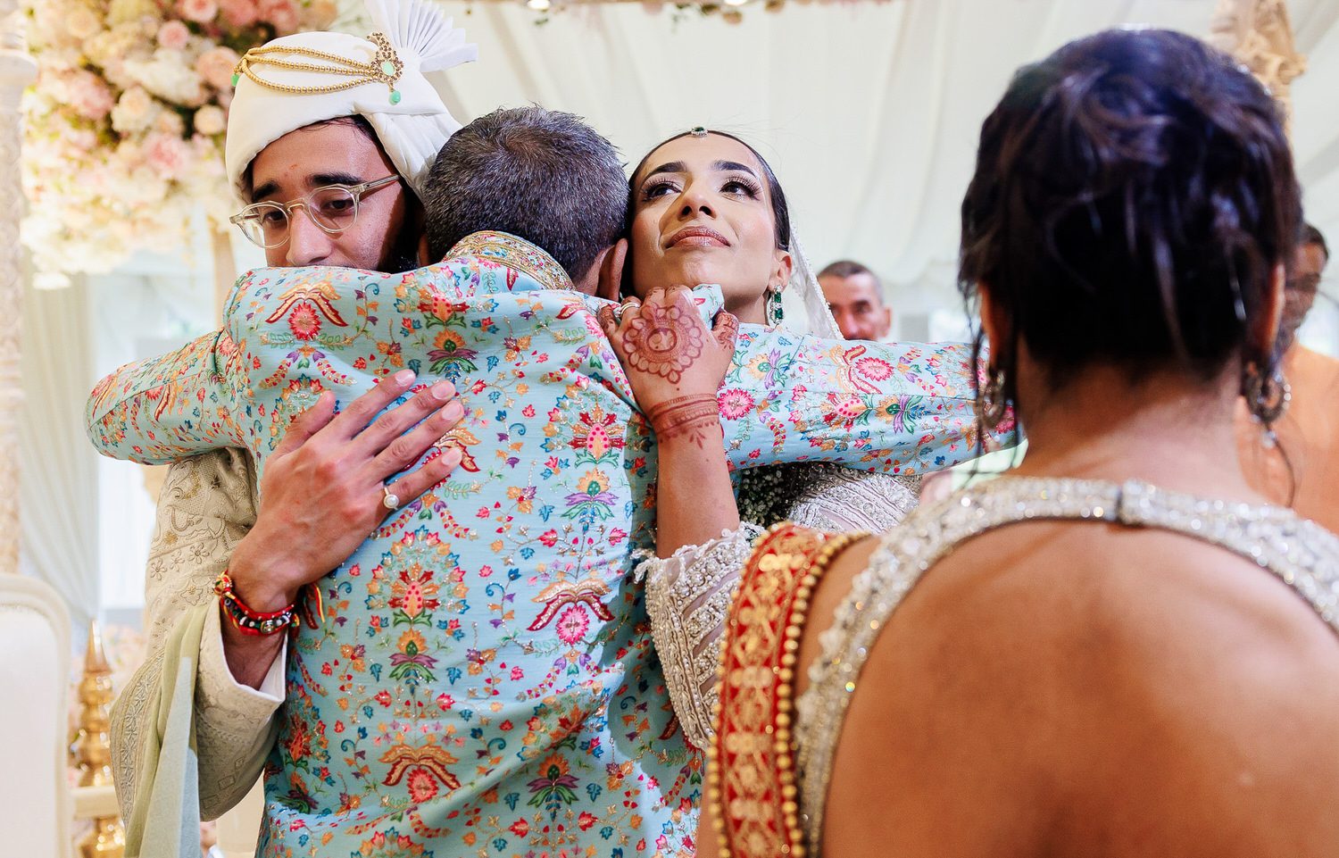 Wedding couple hugging father of the bride