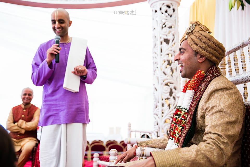 Groom in the mandap laughing with the priest