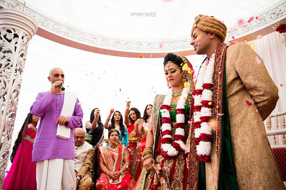 Wedding guests showering asian wedding couple with flowers