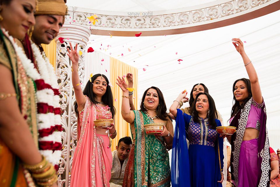 Wedding guests showering asian wedding couple with flowers