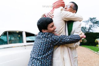 Groom hugging bride's father and cousin