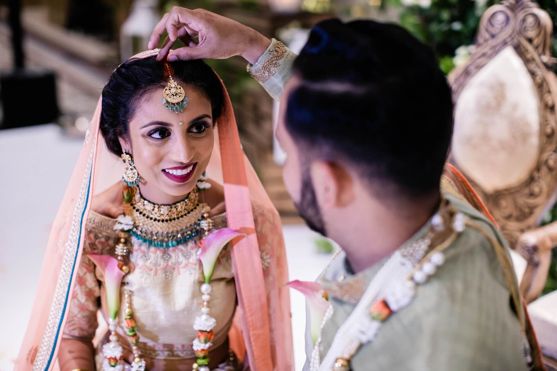 Groom placing sindoor into the parting of the bride's hair