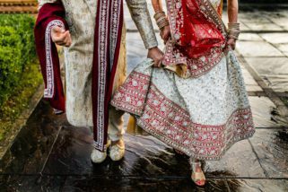 Asian groom holding onto bridal dress