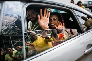 Bride and groom leaving with reflection of parents in the car window