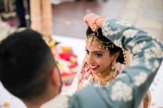 Groom placing sindoor into the parting of the bride's hair