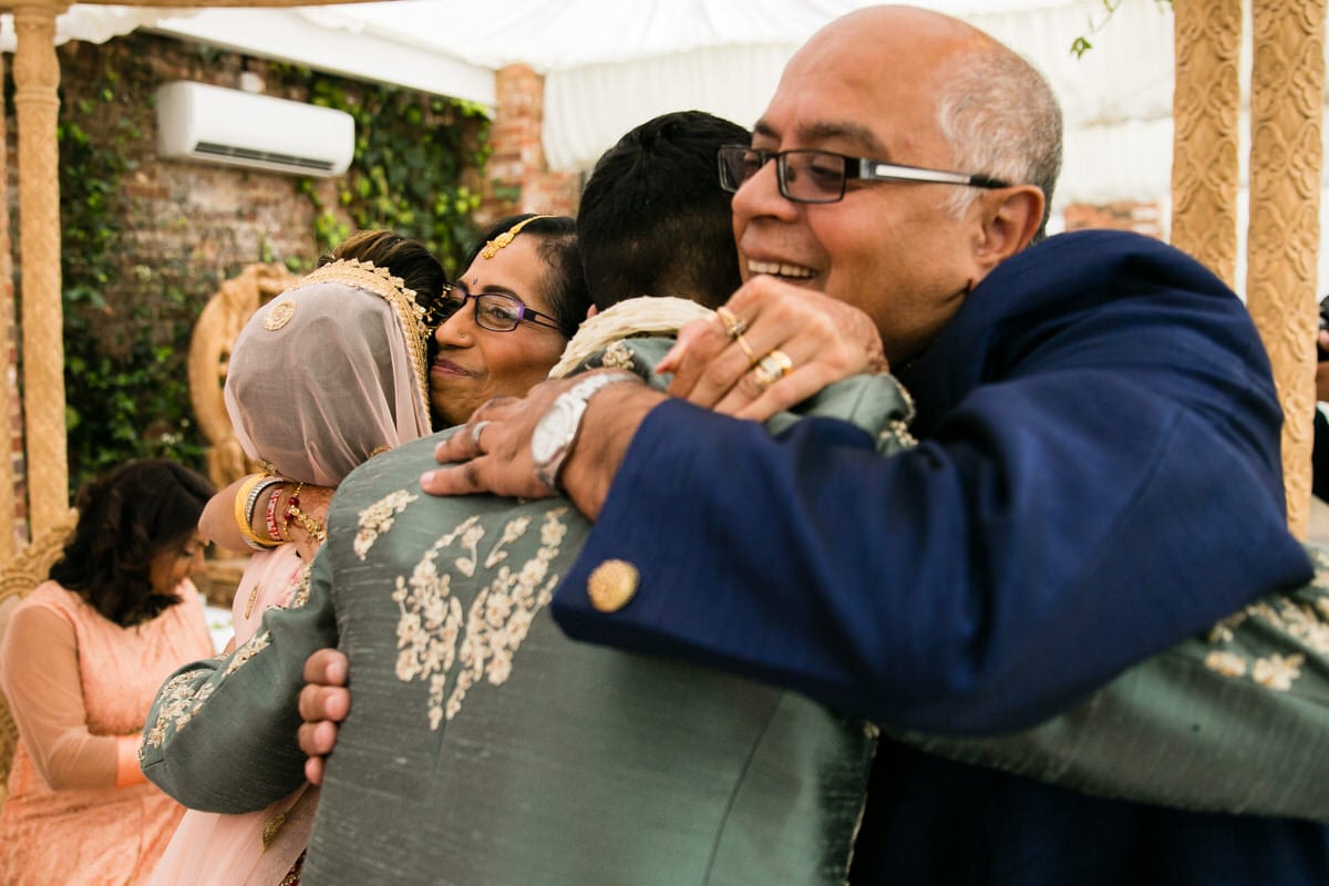 Bride and groom hugging parents