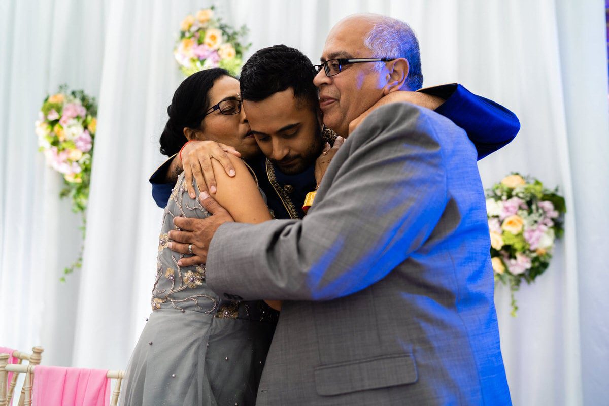 Groom hugging parents