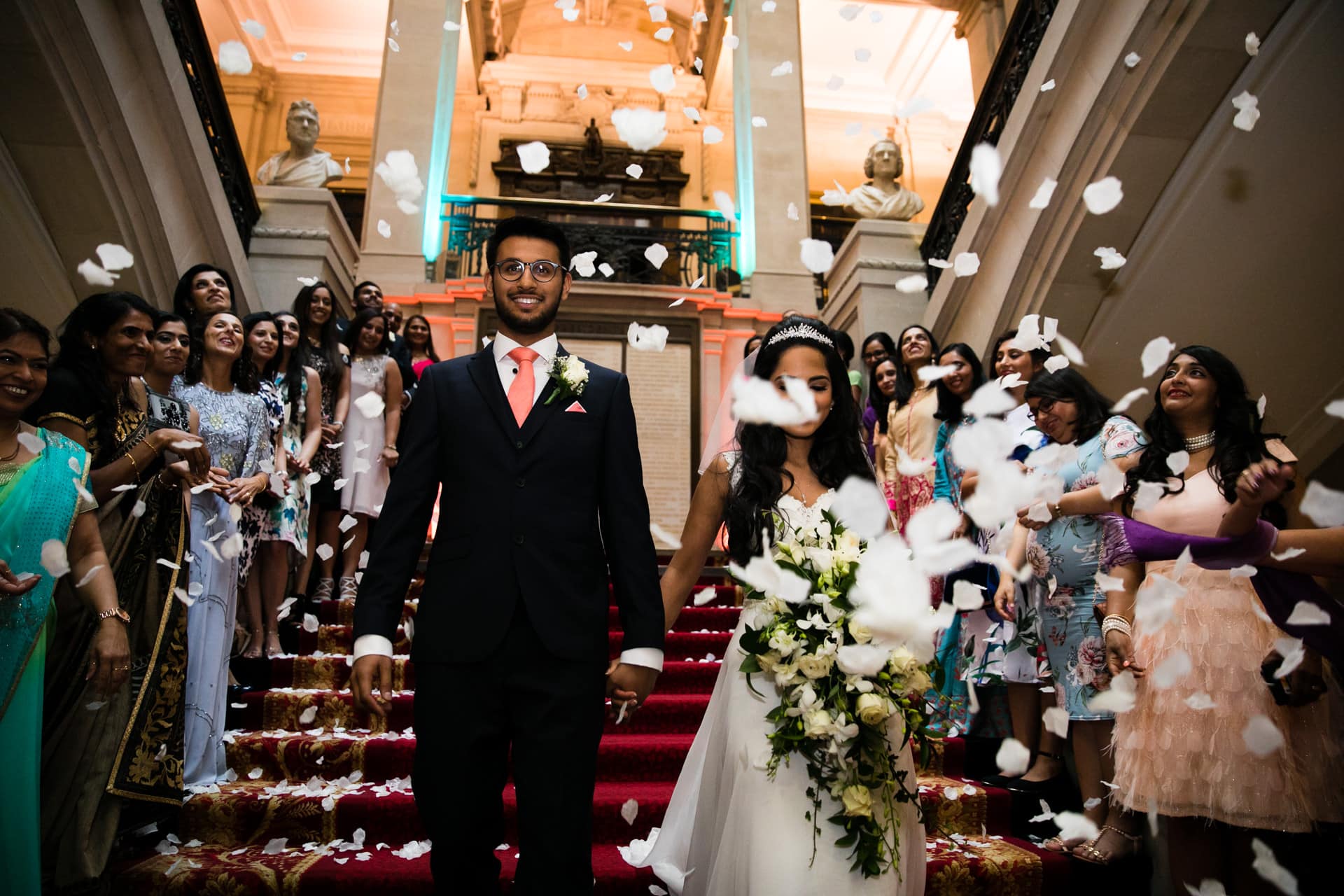 Bride and groom walking while being showered by confetti