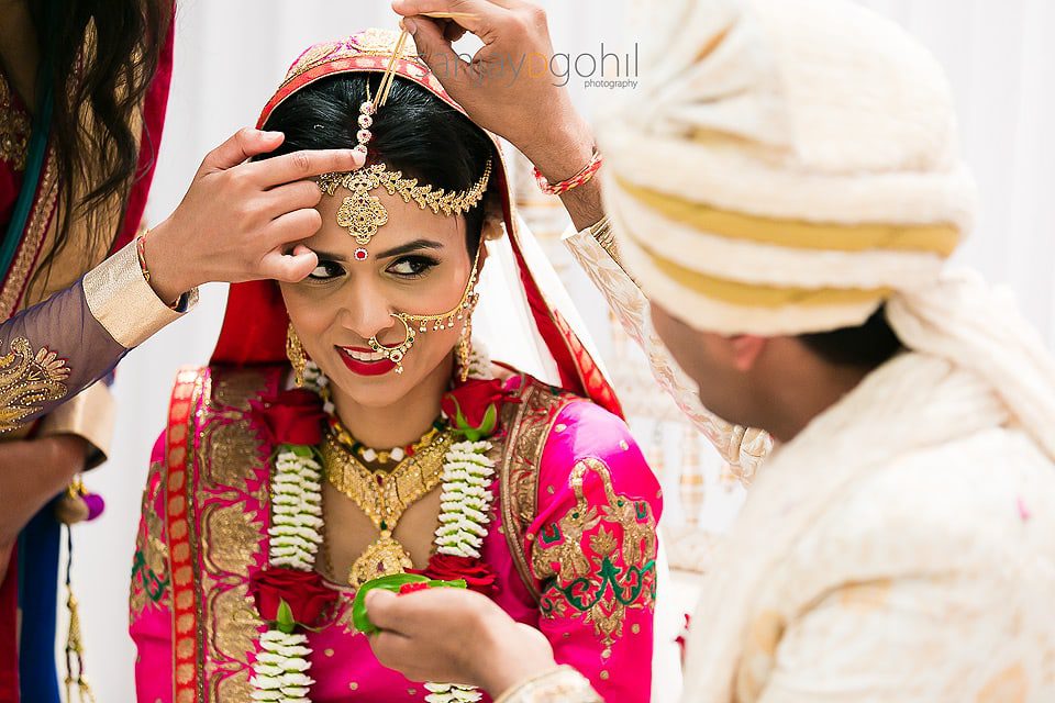 Sindoor being placed on forehead of the asian bride