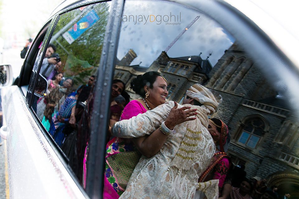 Reflection of bride's mum hugging groom