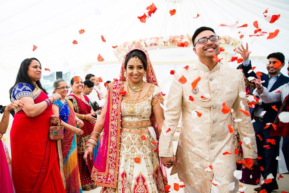 Asian bride and groom leaving while being showered with flowers